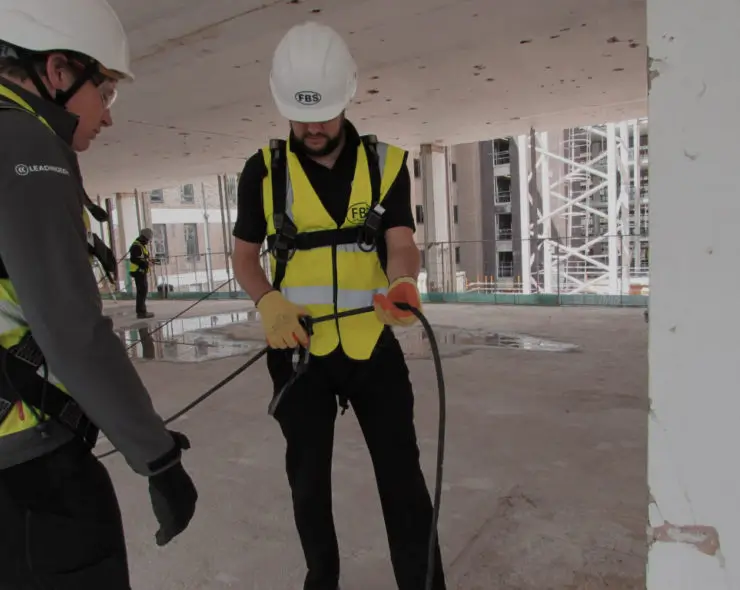 Operative wearing hi vis, hard hat, harness and lanyard during height safety training course.