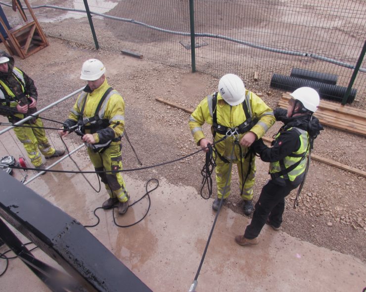 Construction workers taking part in height safety training wearing safety helmet, hi-vis tether jackets