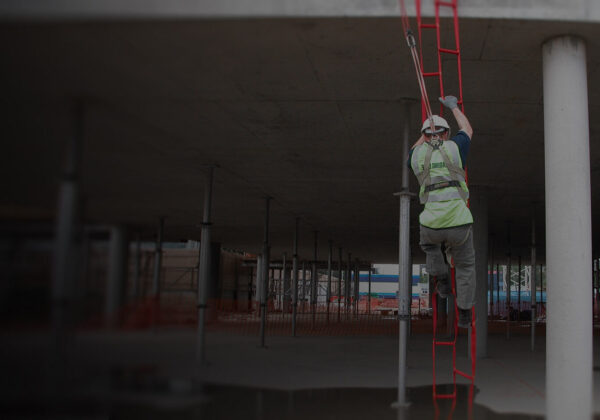 Worker wearing height safety gear climbing safely down a rescue ladder