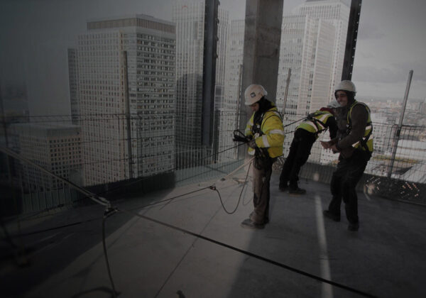 Operative wearing hi-vis, hard hat and harness securing a safe anchorage point