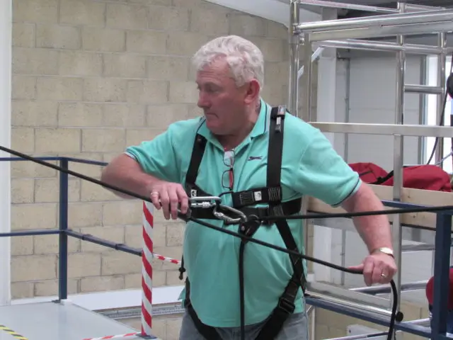 Manager during fall protection training, wearing height safety harness and lanyard
