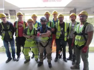Happy operatives wearing yellow hard hats, hi-vis and harnesses during leading edge training course