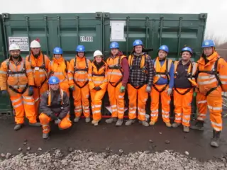 Operatives on leading edge training solutions course wearing orange hi-vis boiler suits, hard hats and full body harness.