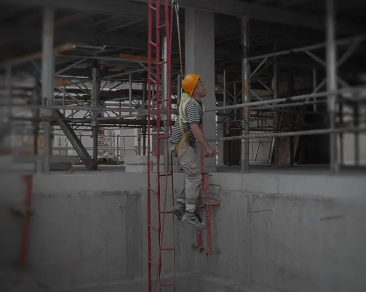 Operative wearing working at height rescue equipment demonstrating ladder climbing safety