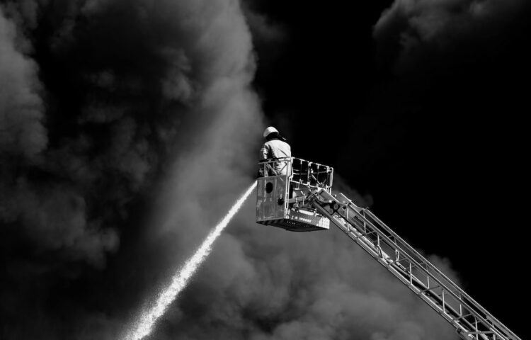 Fire fighter putting out fire from height surrounded in smoke