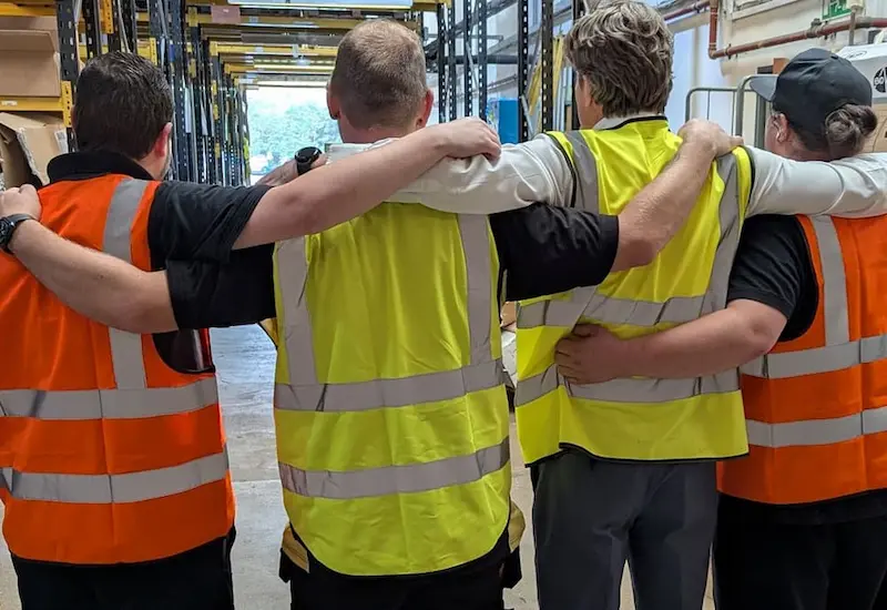 four males in hi-vis shoulder to shoulder