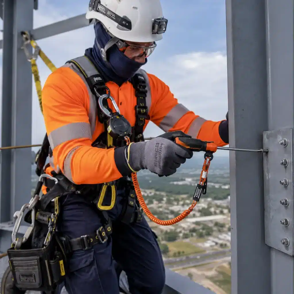 Male working at height holding a tethered screwdriver and wearing ppe