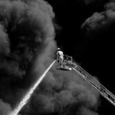 Fire fighter putting out fire from height surrounded in smoke